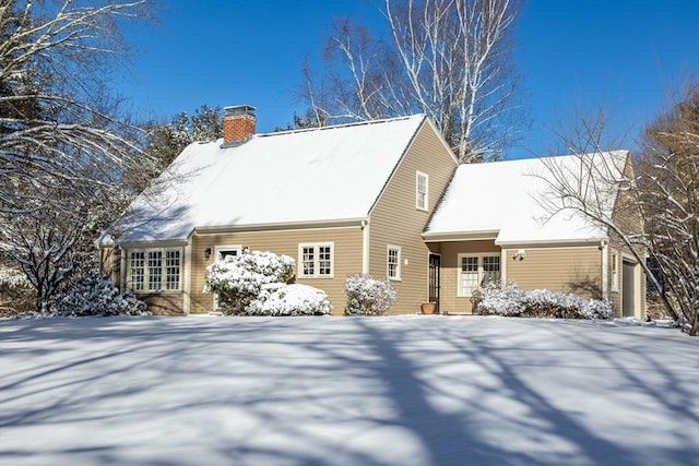 snow covered back of property with a garage