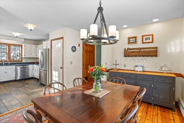 dining room featuring sink, a notable chandelier, and baseboard heating