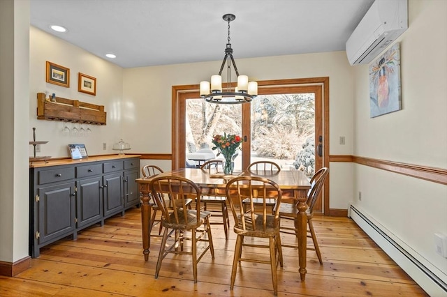 dining area featuring a baseboard heating unit, a wall mounted air conditioner, a notable chandelier, and light hardwood / wood-style flooring