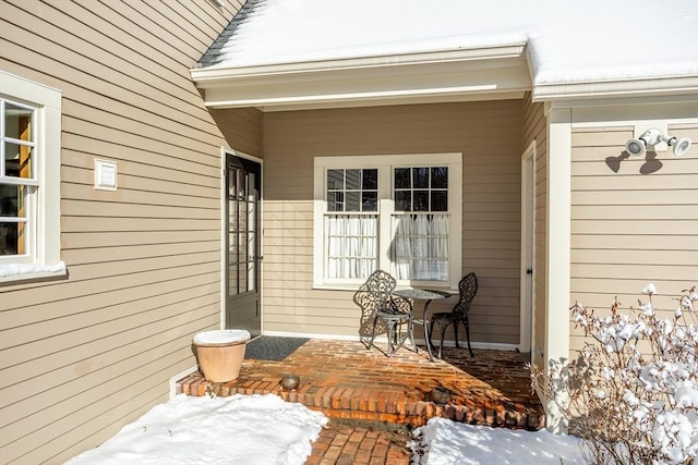 snow covered property entrance featuring a patio