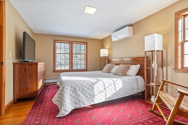 bedroom with wood-type flooring, a wall mounted AC, and a baseboard heating unit