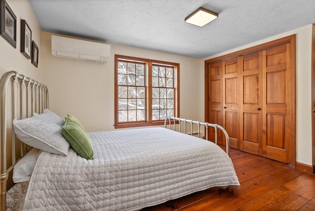 bedroom with a closet, wood-type flooring, and an AC wall unit