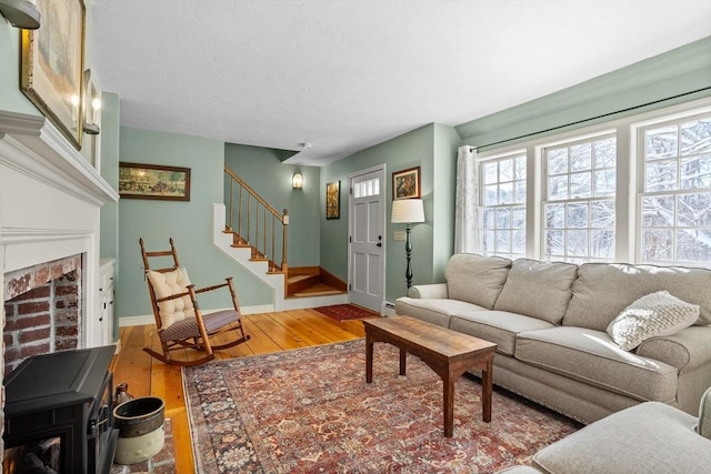 living room with hardwood / wood-style flooring, baseboard heating, and a brick fireplace