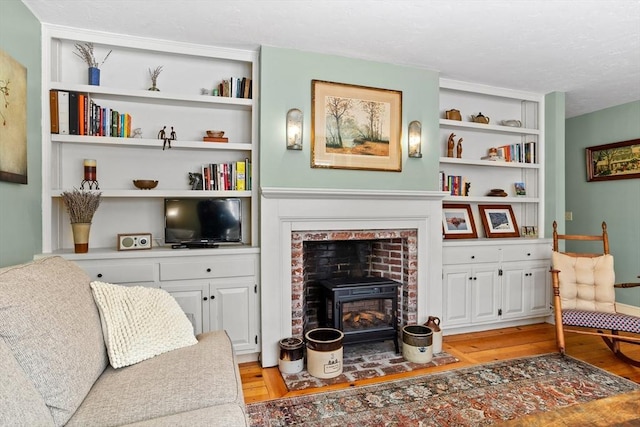 living area featuring a wood stove, built in features, and light wood-type flooring