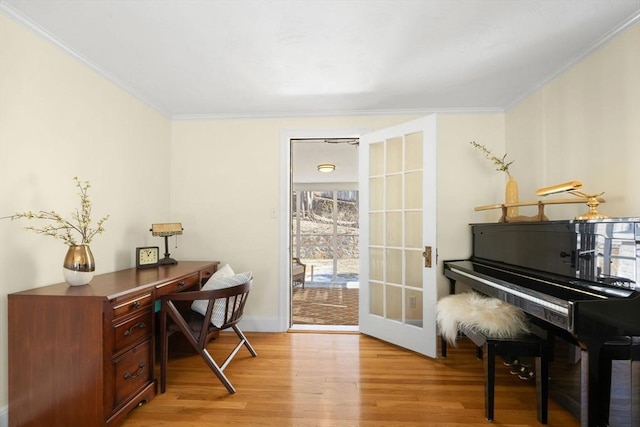 sitting room with light wood-style floors, french doors, crown molding, and baseboards