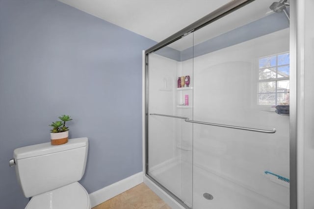 bathroom featuring toilet, a stall shower, and baseboards