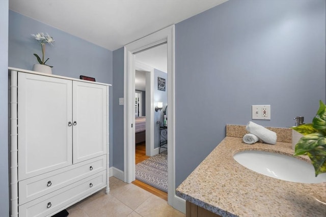 ensuite bathroom with baseboards, ensuite bathroom, a sink, and tile patterned floors