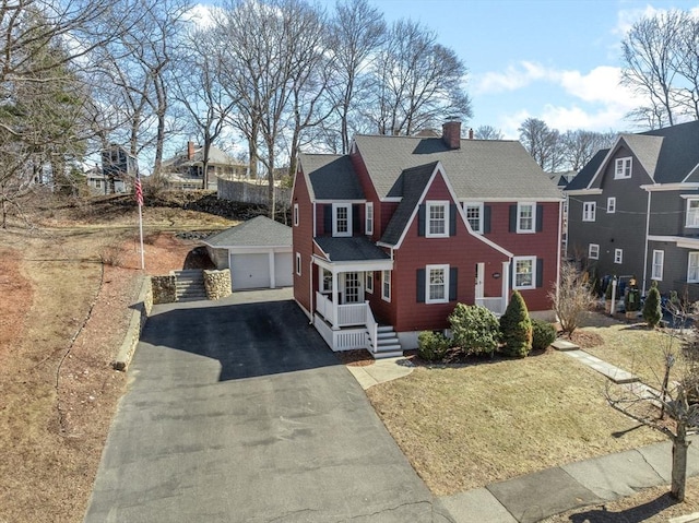 view of front of home featuring an outbuilding, a detached garage, a chimney, a shingled roof, and a front yard