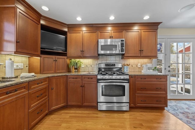 kitchen with light wood-type flooring, brown cabinets, and stainless steel appliances