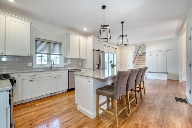 kitchen with visible vents, light wood-style flooring, a sink, stainless steel appliances, and light countertops