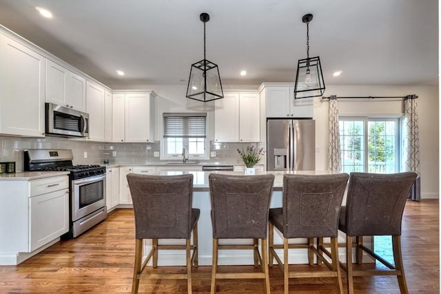 kitchen with a breakfast bar, a sink, tasteful backsplash, a kitchen island, and stainless steel appliances