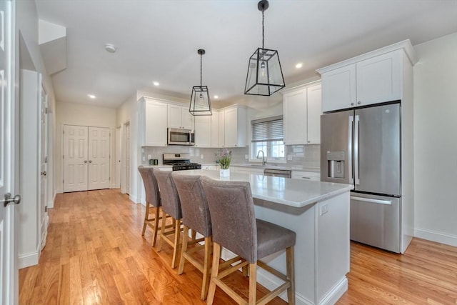 kitchen with a sink, light wood-type flooring, white cabinetry, and stainless steel appliances