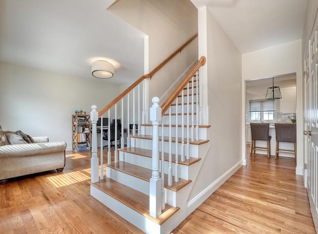 stairway with wood finished floors and baseboards