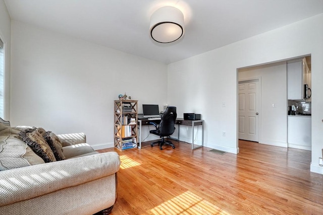 office space with visible vents, light wood-style flooring, and baseboards