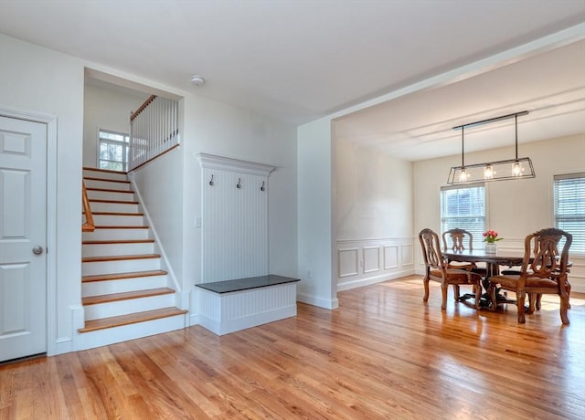 dining space with wainscoting, stairway, light wood-style flooring, and a decorative wall