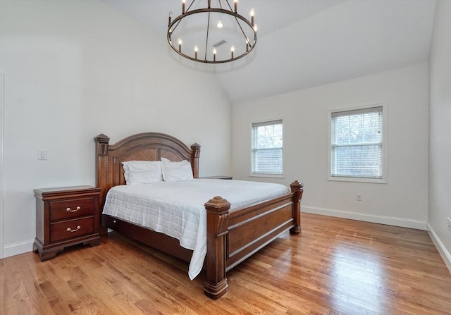 bedroom with light wood-type flooring, baseboards, lofted ceiling, and a chandelier