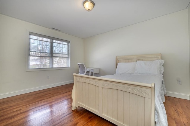 bedroom with visible vents, wood finished floors, and baseboards