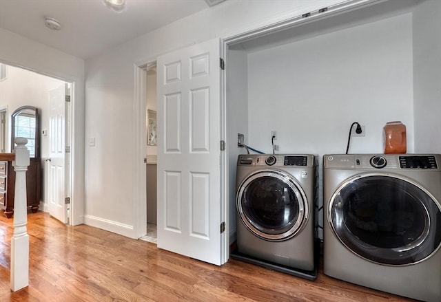 clothes washing area featuring laundry area, washing machine and dryer, light wood-style floors, and baseboards