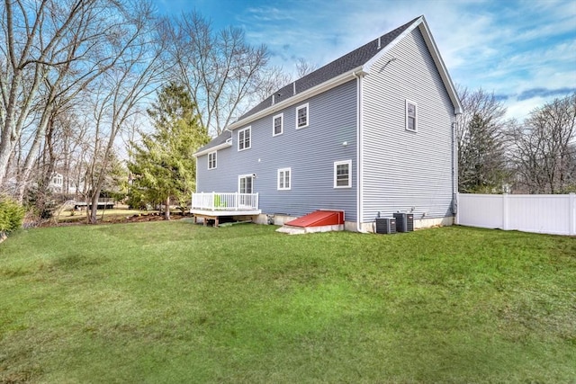 rear view of property with a wooden deck, a yard, and fence