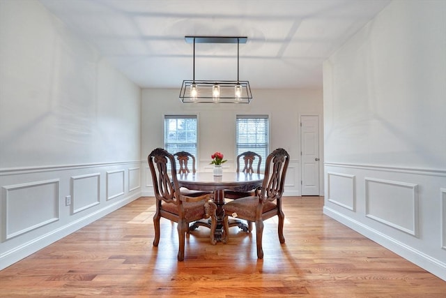 dining room featuring light wood-style flooring and a decorative wall