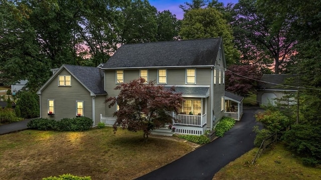 colonial-style house with a yard and covered porch