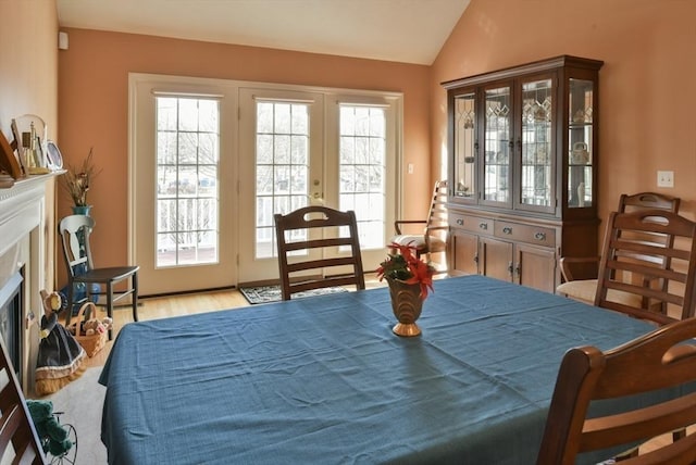 dining room featuring french doors, light wood-type flooring, vaulted ceiling, and plenty of natural light