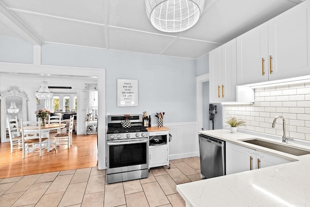 30 Highland St, Abington, MA 02351 - kitchen featuring stainless steel appliances, a sink, white cabinets, a wainscoted wall, and light wood-style flooring