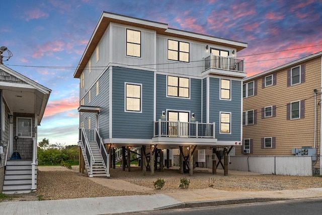 30 Cable Ave Unit B, Salisbury, MA 01952 - back of property at dusk with stairs, a carport, a balcony, and board and batten siding