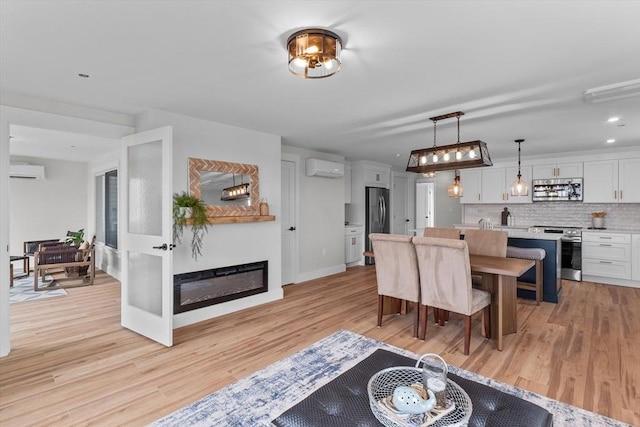 30 Cable Ave Unit B, Salisbury, MA 01952 - dining area featuring an AC wall unit, light wood finished floors, and a glass covered fireplace