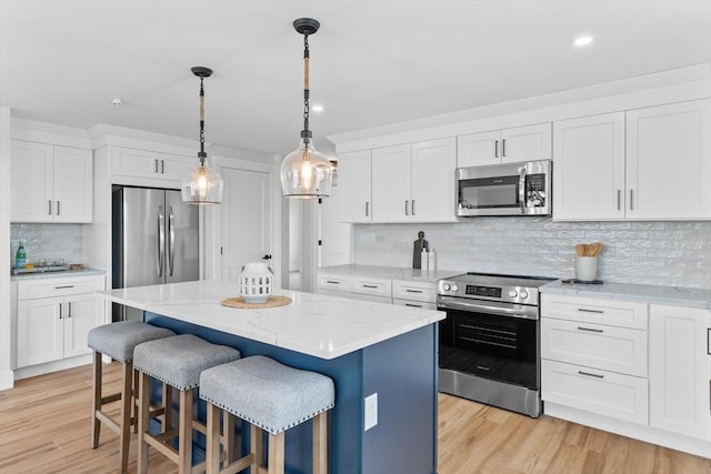30 Cable Ave Unit B, Salisbury, MA 01952 - kitchen featuring appliances with stainless steel finishes, a center island, backsplash, white cabinetry, and pendant lighting