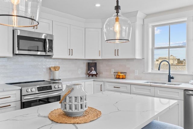 30 Cable Ave Unit B, Salisbury, MA 01952 - kitchen featuring stainless steel appliances, white cabinets, hanging light fixtures, and decorative backsplash