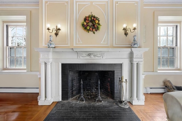 detailed view of baseboard heating, a fireplace with flush hearth, a baseboard heating unit, and ornamental molding