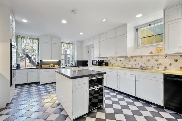 kitchen with black appliances, a sink, white cabinets, and recessed lighting