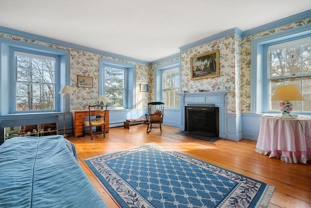 sitting room featuring hardwood / wood-style flooring, wallpapered walls, a fireplace with flush hearth, a baseboard radiator, and ornamental molding
