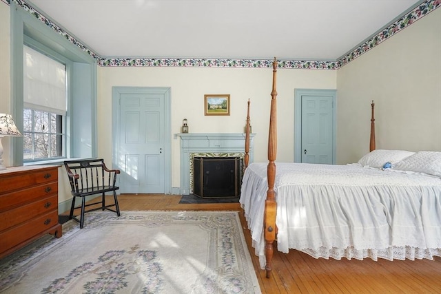 bedroom featuring hardwood / wood-style floors and a fireplace with flush hearth