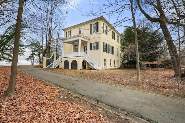 view of front facade featuring stairway, a porch, and stucco siding