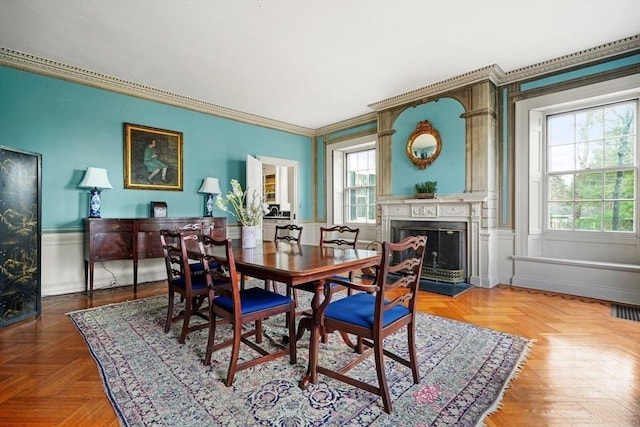 dining area with a premium fireplace, ornamental molding, and baseboards