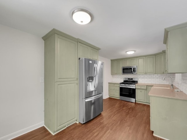 kitchen with decorative backsplash, appliances with stainless steel finishes, dark hardwood / wood-style flooring, sink, and green cabinets