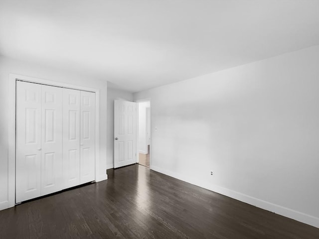 unfurnished bedroom featuring a closet and dark wood-type flooring