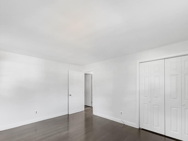 unfurnished bedroom featuring dark wood-type flooring and a closet