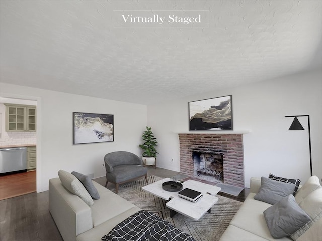 living room featuring wood-type flooring, a textured ceiling, and a brick fireplace