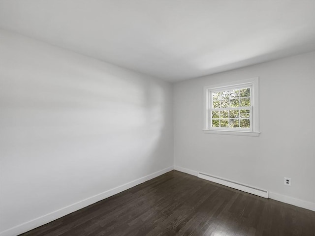 spare room featuring dark wood-type flooring and a baseboard radiator