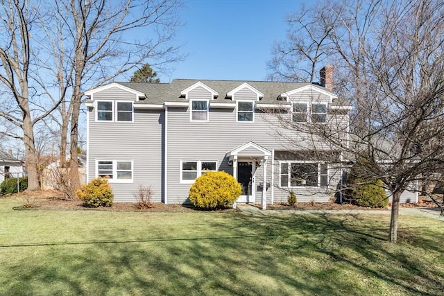 view of front of home featuring roof with shingles, a chimney, and a front lawn