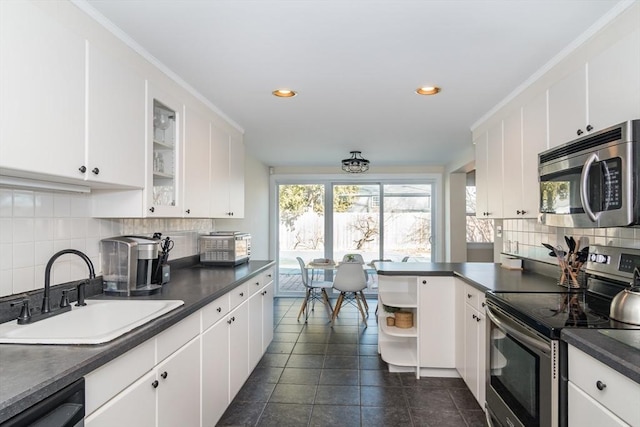 kitchen featuring dark countertops, appliances with stainless steel finishes, white cabinetry, and a sink