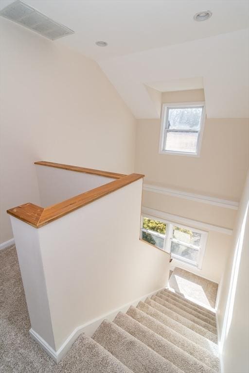 stairway with vaulted ceiling, carpet, baseboards, and visible vents