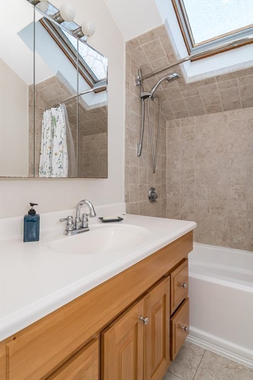 bathroom with vanity, tile patterned floors, a skylight, and shower / tub combo