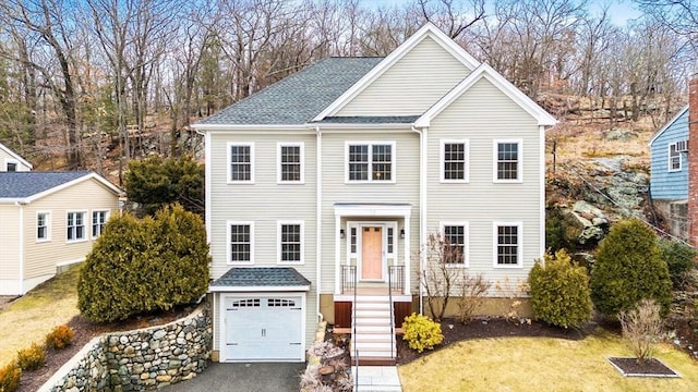 view of front of home with driveway, a front lawn, roof with shingles, and an attached garage