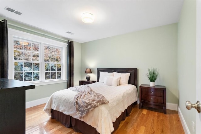 bedroom featuring light wood-type flooring, visible vents, and baseboards