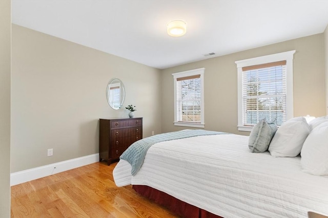 bedroom with visible vents, light wood-type flooring, and baseboards