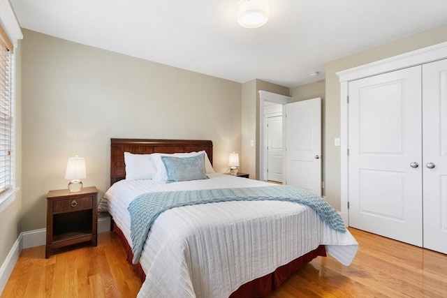 bedroom with a closet, baseboards, and light wood-style floors